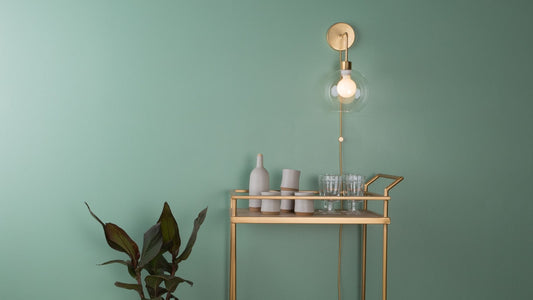 A plug-in wall sconce with globe shade by Color Cord featuring parts of a light fixture like an exposed bulb, cord stay, and cloth covered wire.